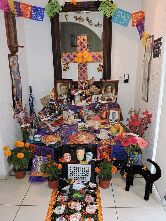 Una ofrenda familiar en casa con fotos, flores y velas