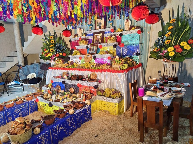 Una ofrenda grande con flores, papel picado y comida en Puebla
