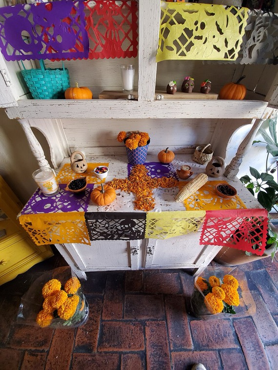 Una ofrenda con papel picado de colores, calaveritas y cempasúchil